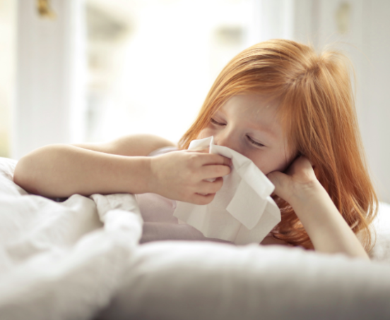 Mała dziewczynka z katarem trzymająca w ręce chusteczkę.